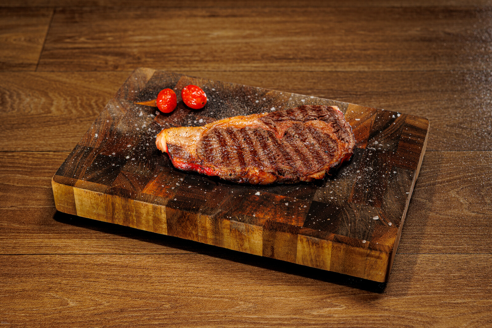 Bistecca alla griglia servita su tagliere di legno con pomodorini