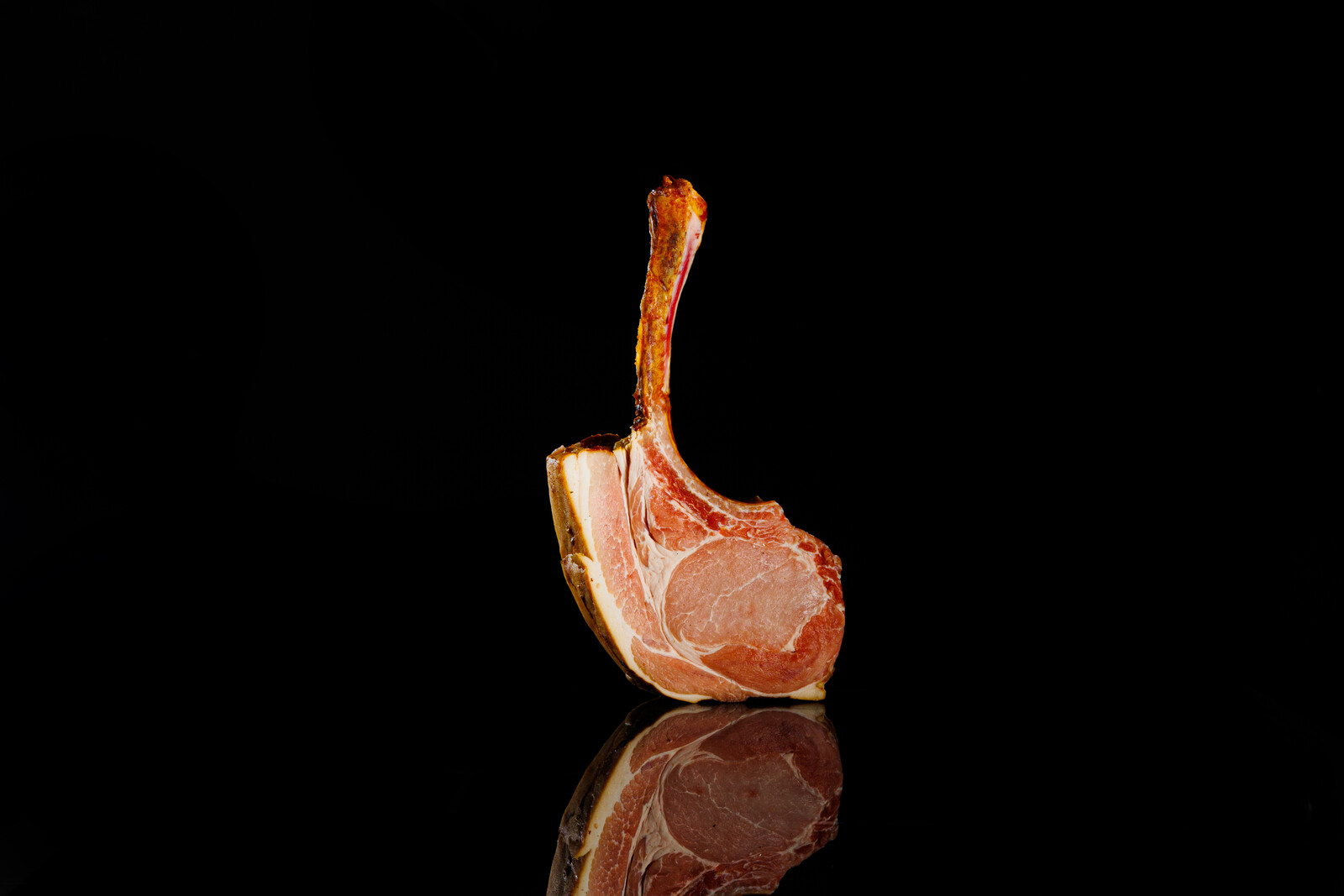 Tomahawk crudo appeso per l osso su fondo nero