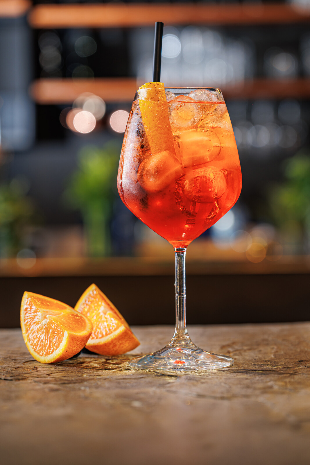 Cocktail arancione con ghiaccio e arancia in calice da vino