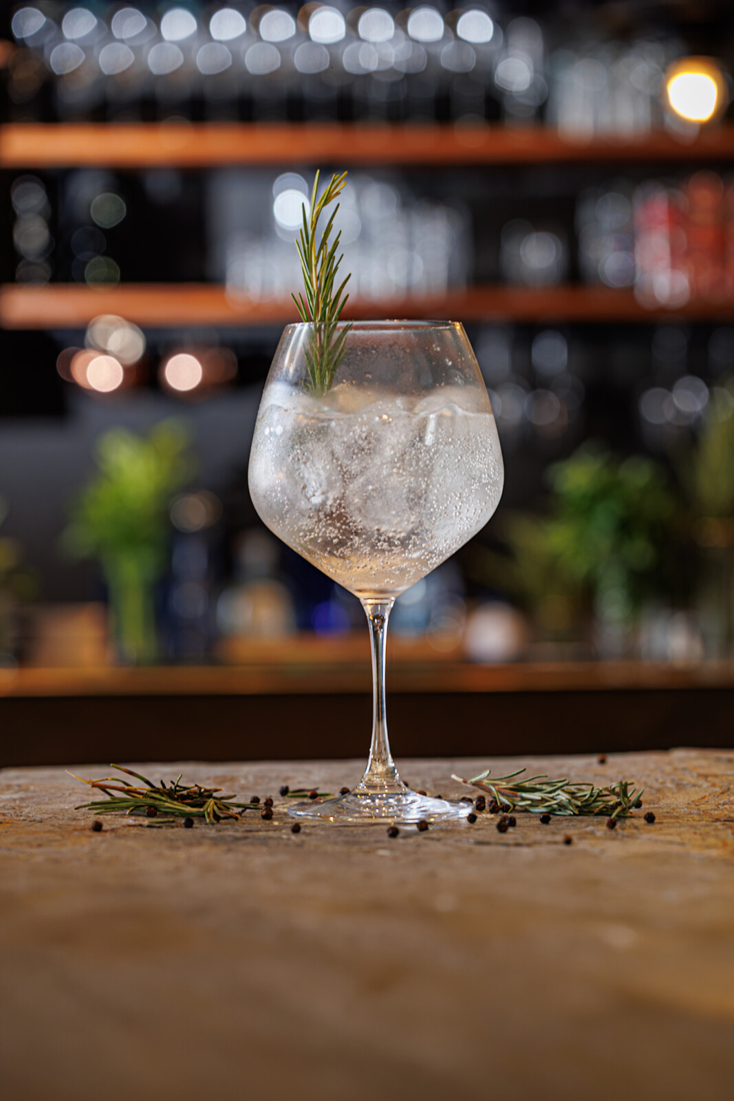 Gin tonic trasparente in calice con rosmarino