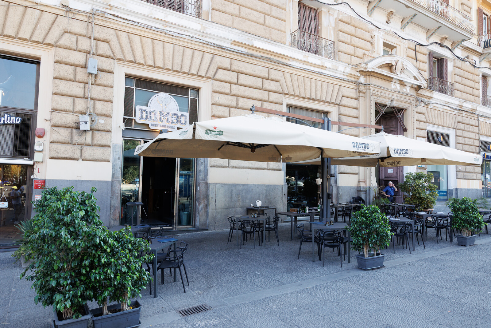 La facciata del palazzo con il dehors e gli ombrelloni