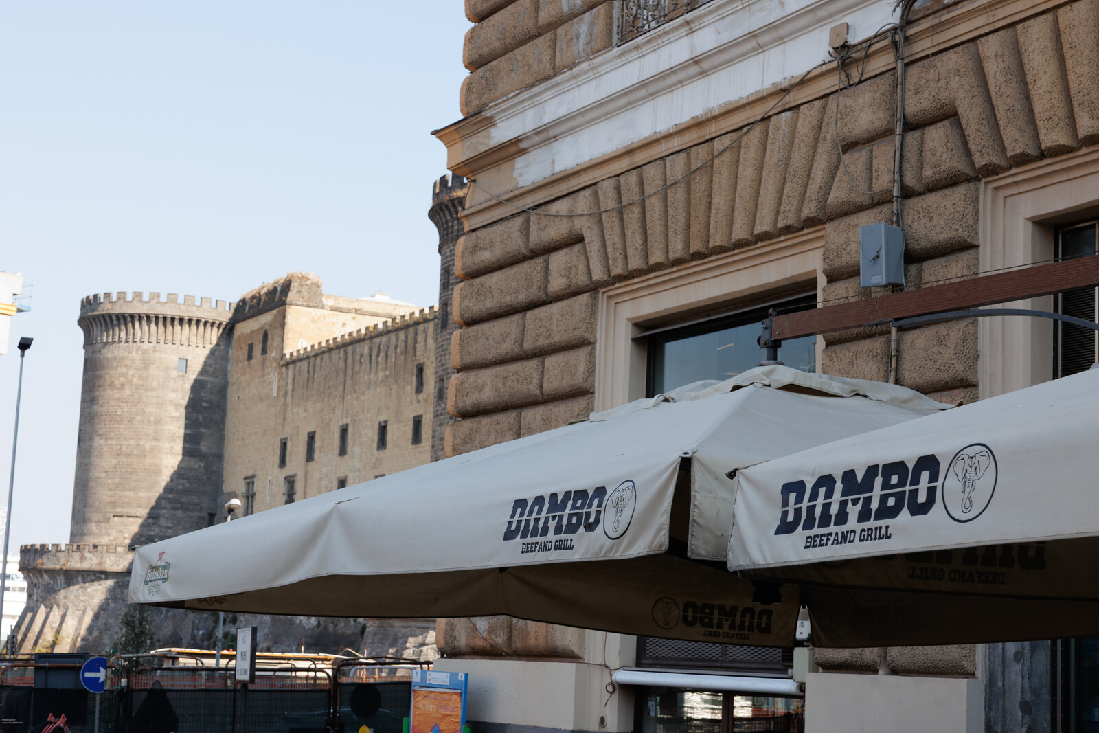 Il dehors di Dambo con gli ombrelloni, e sullo sfondo il Maschio Angioino