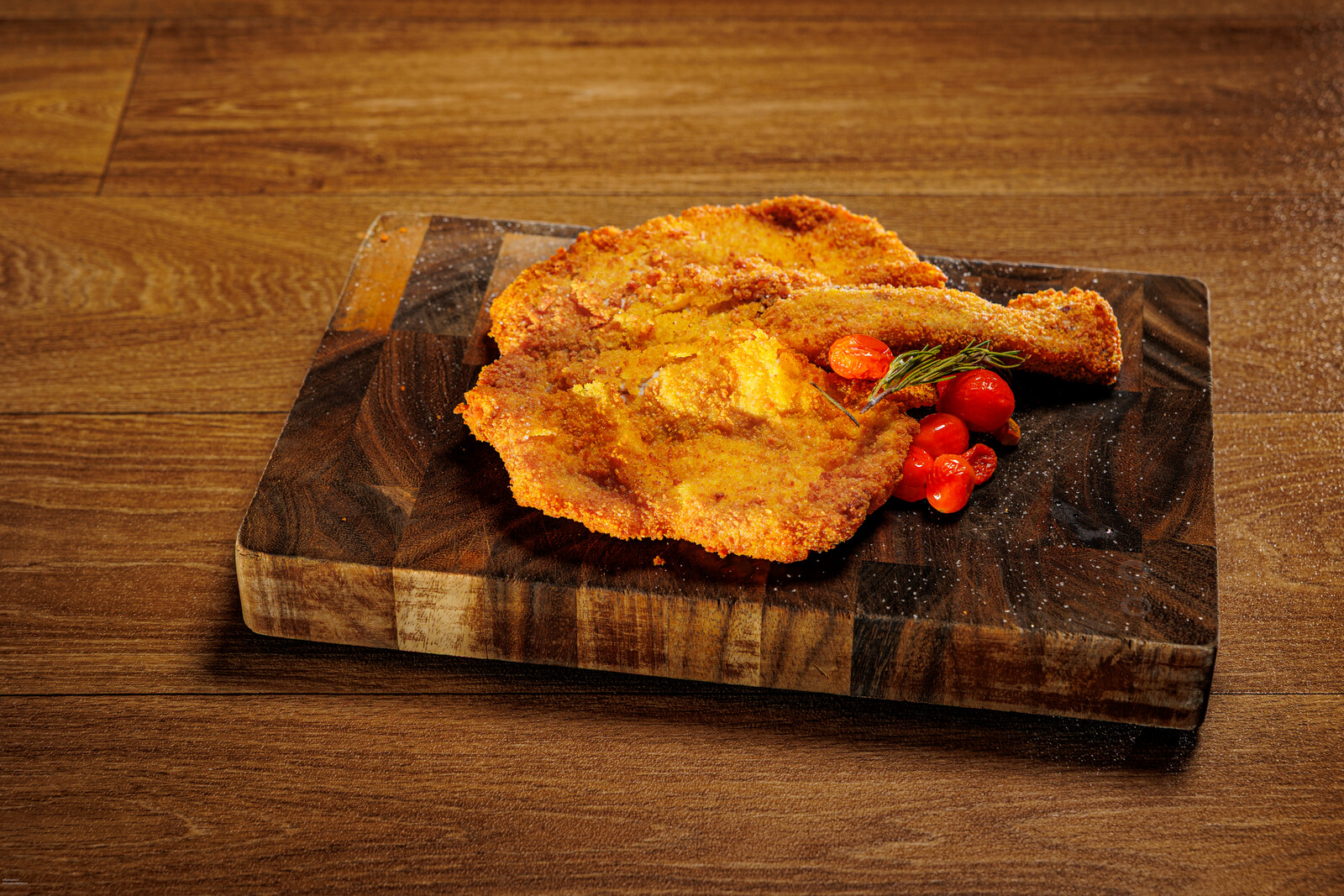 Cotoletta impanata su tagliere di legno con pomodorini